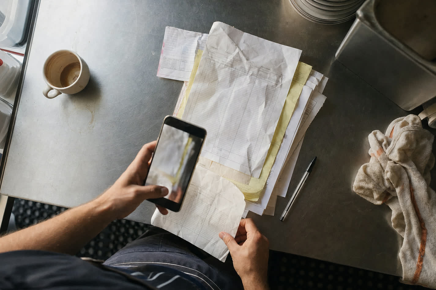 Factures fournisseurs photographiées au téléphone sur un comptoir